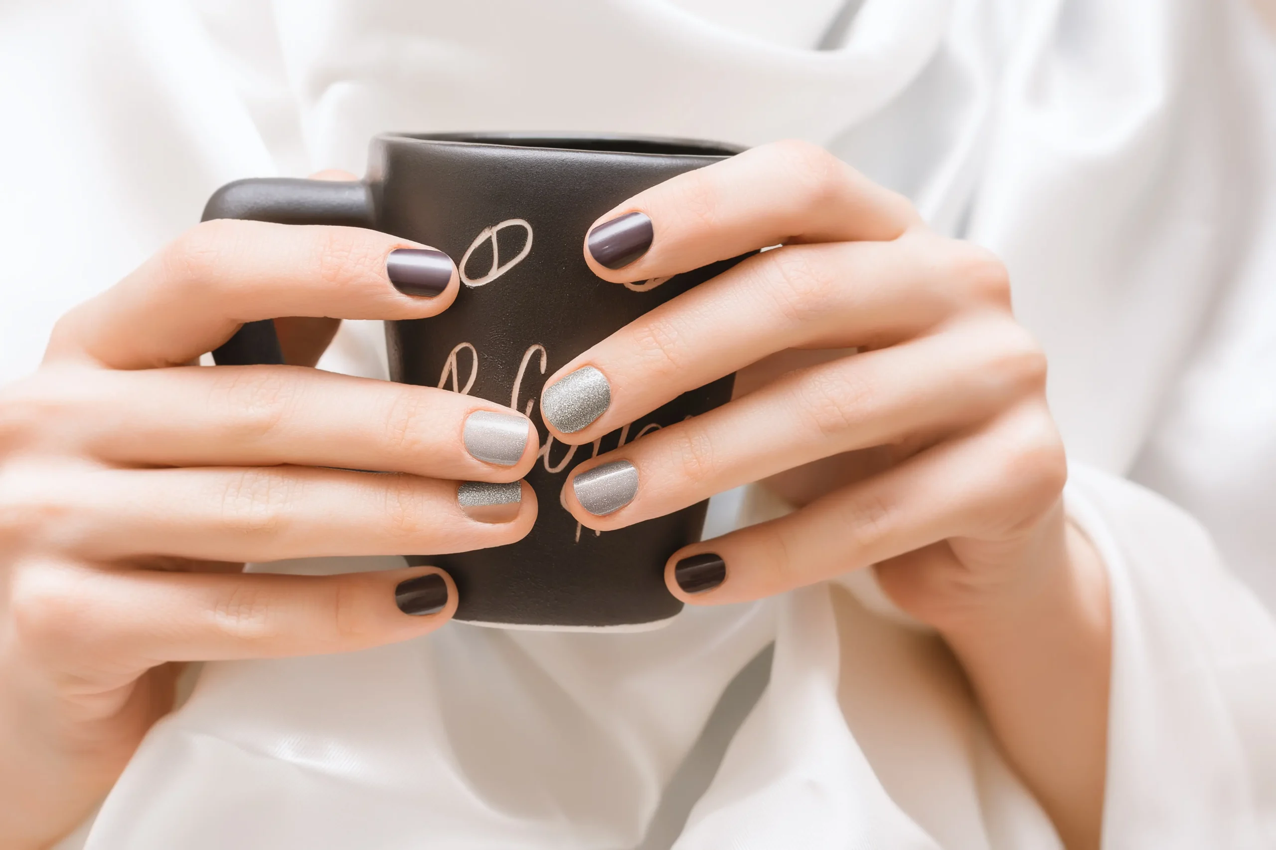 female-hands-with-glitter-nail-design-holding-black-cup-scaled-1.webp